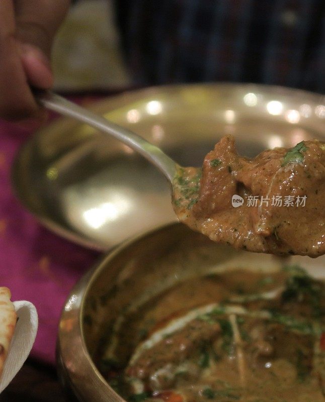 印度餐厅的菜肴，murgh methi masala chicken tikka咖喱食谱(香料香料的masala chicken with葫芦巴和奶油)，男子为自己服务，并把自制的烤鸡与勺子照片，大蒜馕饼，金属塔利菜和盘子